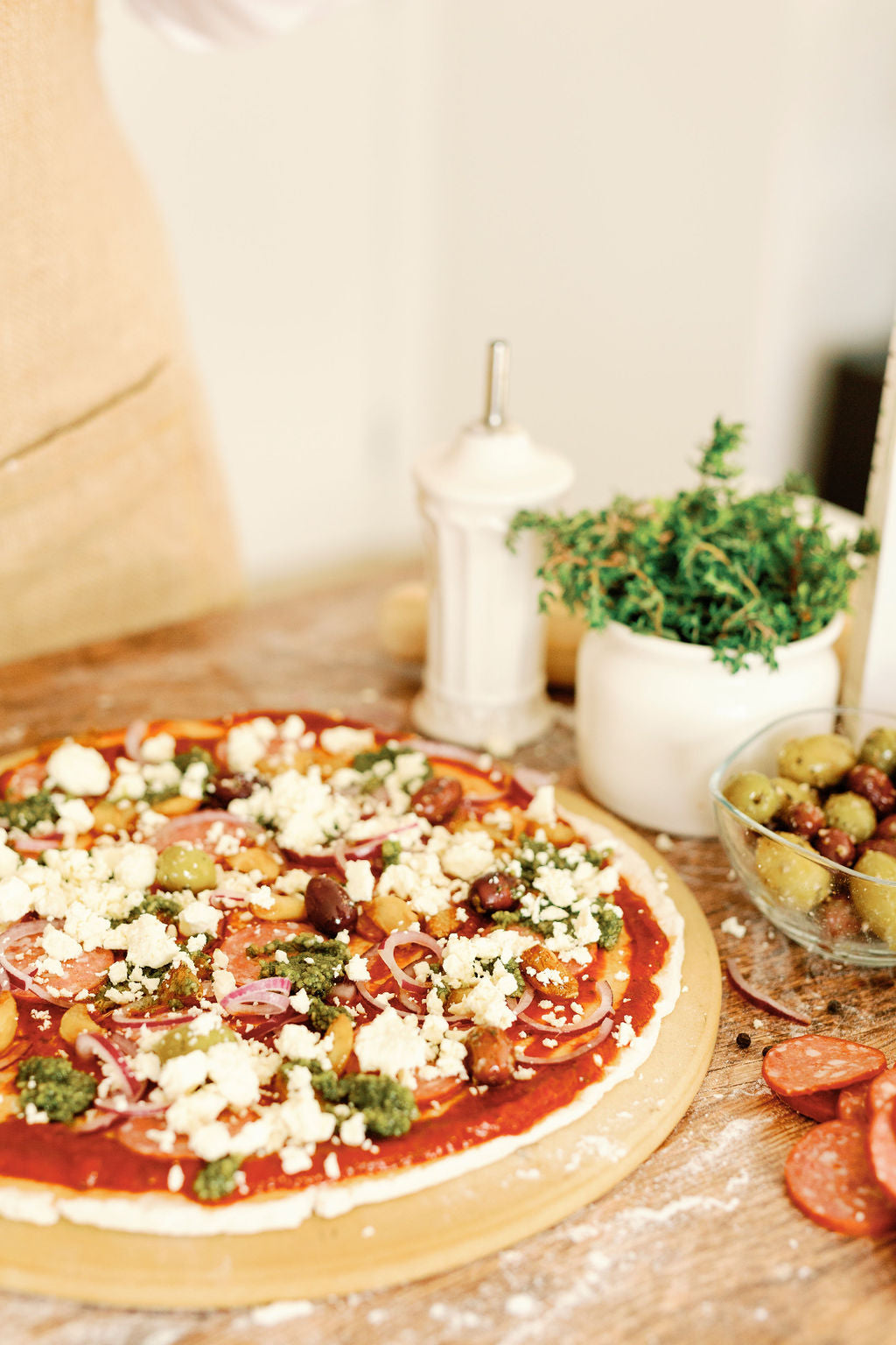 Pizza cut into 8 slices on white paper and a wooden table. Pizza cutter in top corner