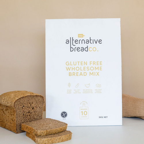 Gluten free wholesome bread mix in a large 10kilo bag with a sliced loaf in front and a cloth brown napkin behind 
