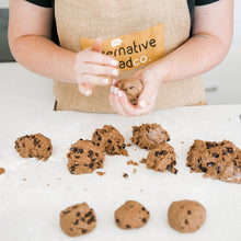 Load image into Gallery viewer, Rolling gluten free hot cross buns  into balls. 3 rolled in the front, 6 ready to roll an done being rolled in hands of the lady baker.